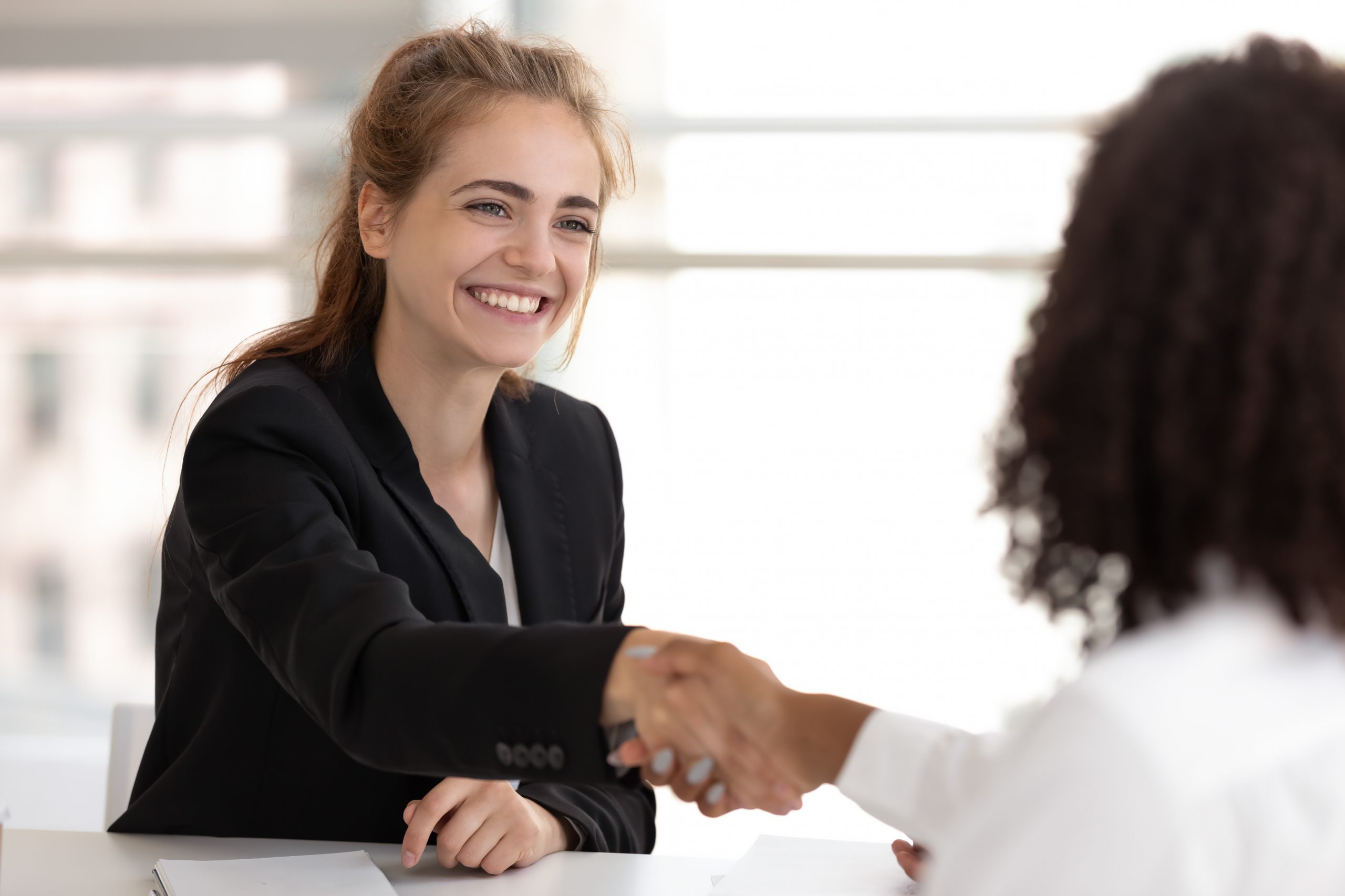 Happy businesswoman hr manager handshake hire candidate selling insurance services making good first impression, diverse broker and client customer shake hand at business office meeting job interview